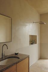 The sink units in one of the bathrooms neatly brings together all the work done by Skye Stone Studio and 56 North Kitchens, with the doors being leftover pieces of the oak laminate. The View Mirror is a Soren Lassen design for Audo Copenhagen. The shower and sink fittings are by Hansgrohe.