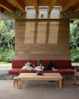 A couch made of custom cushions supported by a stone ledge and a rammed earth wall is an ideal reading spot on the patio.