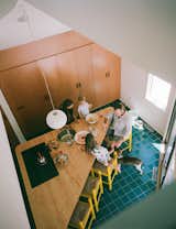 Wherever possible, the family retained original details, like the textured teal floor tiles and triangular island in the kitchen. They weren’t able to save the plywood millwork, which had deteriorated, but liked the look, so Baab added new cabinetry in a similar finish. The previous residents left behind much of their furniture, including the yellow barstools. The pendant is a Glo-Ball from Flos.