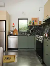 In the open-plan kitchen, Knight combined green Ikea cabinets with an affordable leathered granite, along with Samsung appliances and Lumens sconces. “Having ample space for day-to-day activities was important, but so was having space that flows,” he says.