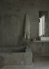 The bathroom is lined in roughly applied concrete.