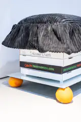 The stool pictured here is made of exactly what it looks like—pizza boxes sourced from the streets of New York, with a reinforced, upholstered pillow on top. (The oranges are there for a bit of flair.)