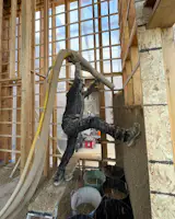 A builder sprays hemp into a new home’s framing.
