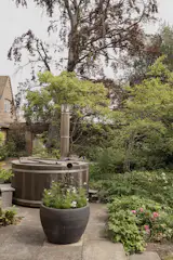 A wood-fired hot tub sits in the garden.