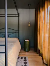 The color story continues in her deep-green bedroom, which features a vintage cast-iron canopy bed, olive-green Componibili side tables from Kartell, and Gaia pendants by Tala.