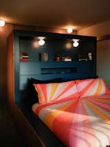 In the primary bedroom, the built-in bed and storage-filled headboard are painted a royal blue. All the original colors in the home were kept, except here, where Pete painted the blue ceiling and upper part of the wall white to make the room a little brighter. The asymmetrical globe lights were handcrafted in Turkey, and the bed linens are by Trina Turk. “I was drawn to the idea of sleeping in the sun,” says Pete.