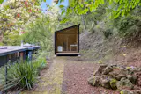 An office pod sits in the backyard, just up a hill.