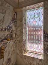 In the primary bathroom, defined by the pink stained-glass window, the architect and her team painstakingly sourced slabs of Vagli Rosato pink-and-purple marble to wrap the walls around the shower and bathtub.