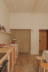 Instead of completely refinishing the floors in the kitchen which, like the rest of the flat, were hidden under wall to wall carpeting, the team left them mostly as is. (The patina here is just traces of a particularly stubborn adhesive.) The linen and wool curtains are made of material sourced from a mill in Dundee and conceal the pantry and laundry.