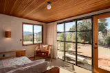 The windows, like this floor-to-ceiling one in the bedroom, are steel framed, opening up to the landscape.