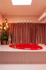Believe it or not, this bathroom—which was a major draw due to its size—was fully carpeted when the couple moved in. The couple drove to Illinois to pick up the heart-shaped tub, which was found on Facebook Marketplace. The tile surrounding it Fireclay in the color Evening Glow. The lights are from Velora; the curtain surrounding the tub was custom made by Loom Decor, using fabric Crypton. The vintage-inspired ceramic leopard is from Dogwood Lifestyle.