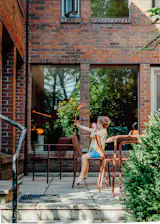 On the patio, a table and chairs from Hay complement the red brick facade.