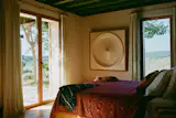 A 1970s white fiberglass plafond lamp, salvaged from a hotel lobby ceiling in Italy, anchors the primary bedroom. “It is one of my favorite pieces and one which I enjoy every day, since it’s the light that I leave on before I go to sleep,” says Roberta. The bed is by Ivano Redaelli.