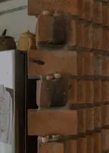 A brick partition separates the refrigerator from the living space.