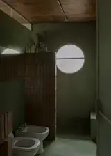 More brick in the bathroom is set against a green finish, one of the only moments of color Ignacio wanted in the home.