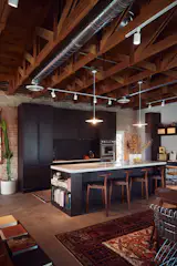 The kitchen has vintage pendants from Rejuvenation and counter stools from Denver Modern. The backsplash and kitchen island inset are made from Oscura Rectangle Cotto tiles from Zia Tile. The kitchen appliances are from Thermador. The Minta faucet is from Grohe. Coppola Custom Woodworking made the oak cabinetry.