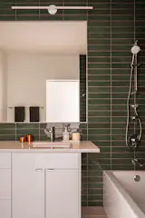 In one of the guest bathrooms, earthy green tiles mimic the verdant hues found in the forest outside.