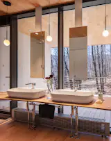 The primary bathroom features industrial-chic double sinks and mirrors, alongside pendant lights by Pablo Design.