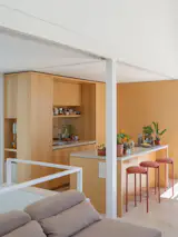 The kitchen ceiling is lower than in the rest of the living area, lending the space a cozy, intimate feel. The countertop is Crema Pisa by Purastone and the stools are by Taller A Prima.