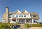 At the inviting entry to Smiros’ clients’ Quogue getaway, oval windows trimmed in AZEK tie into the deep rake of the roof above, and the rounded AZEK-clad porch below. "It looks like a cottage that could've been there for a very long time," Smiros says of the elegant waterfront residence. 