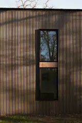 Double windows are set into the corrugated facade, with a band of wood dividing them.
