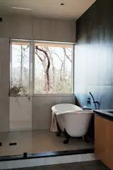 The primary bathroom features a claw-foot bathtub with a big window looking over the property. "Having the big window in there has been amazing," says Jenna. "Just lying there in the bubble bath and watching the birds fly by is so peaceful—and worth the time in the camper trailer." 