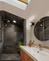 Chelsea’s father tiled her bathroom, which helped keep costs down. She chose Mediterranea’s Modern Slate tile for the shower and floor. The sink, faucet, and cabinet are Ikea; the wall sconce is from Dainolite; and the mirror is an Ebern Designs Seena surface-mount framed medicine cabinet.