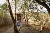 Zaida walks along a leafy, alfresco path that connects the two structures.