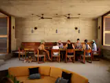 A communal gathering space at the center of the home includes a dining area, a kitchen, and a circular conversation pit upholstered in a mustard color that is carried through to the private rooms. “The house gives you freedom,” says resident Juan Carlos Martín. “You can choose to be social, or you can keep to yourself in your villa.” The dining chairs are by Taller Nacional. The dining table was designed by Gabriela Peña Garavito, made by Francisco Romo. The Aura Wall 22 sconces are from Bandido, and the Can pendant lamps are from davidpompa. The ceiling fans are from Ventilacion Decorativa. The ceramic tableware is by Derrumbe Ceramica.