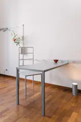 The main aspects of Shakerism were communal spaces and shared resources. Those ethoses were on view with  wall-mounted rail systems that acted as interior storage. Through aluminum, Joshi Greene extended the flexible form to more static furniture, like a two-legged desk and a flower vase.