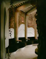 Through the front door and off to the left is the lounge, which has a hearth nested within the home’s river-rock core. The wavy white wall was originally covered in cascading, plush seating, and the floor was shag carpet.