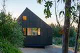In contrast to the bright interior, the architects chose dark exterior cladding to blend the cabin into its natural surroundings. The pine planks are finished with a high-quality, oil-based stain, and in the spirit of minimal intervention, the house sits on a wooden platform secured onto galvanized steel pillars.