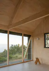 The interior of the cabin, with its 19-foot-tall pitched ceiling, is covered in plywood panels that were glued to the structure’s wood frame—no nails or screws—to achieve a clean, seamless look.