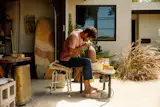 Joe, a ceramic artist and fishmonger, turned the garage into his studio. He often pulls his pottery wheel into the sun to work.