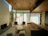 Another view of the main living area shows the connection between the ground and second floors, which are daylit by the same slim skylight above them. The steel coffee table and minimal sofa were custom made. The leather chairs were flea market finds.