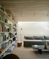 The family room on the second floor overlooks the main living area below through a slender opening delineated by a railing. Both floors receive natural light through a rectangular skylight.