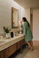 The marble counters are from Franca Stone, and the walnut mirror frame is by TCC Homes. The <span style="font-family: Theinhardt, -apple-system, BlinkMacSystemFont, "Segoe UI", Roboto, Oxygen-Sans, Ubuntu, Cantarell, "Helvetica Neue", sans-serif;">SØKTAS </span><span style="font-family: Theinhardt, -apple-system, BlinkMacSystemFont, "Segoe UI", Roboto, Oxygen-Sans, Ubuntu, Cantarell, "Helvetica Neue", sans-serif;">sconce is from Nook Collections.</span>