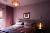The bedroom walls are painted in Brassica from Farrow & Ball. The Pumpkin 2000 print over the Coco-Mat bead is by Yayoi Kusama, and the Suzani coverlet is from Pequeña Inglaterra. The vintage side tables are from Bucks County Estate Traders. The Knit-Wit pendant lamp is from Ameico, and the Enna LED wall sconces are by Astro Lighting.