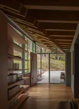 The front door is framed by interlocking Douglas fir beams, which continue inside above a custom built-in bookshelf.