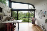 In the artist's studio, a bespoke Marvin Ultimate clerestory carries the curve from wall to ceiling in a single unit—one of the specialty shapes built to the home's exact geometry.