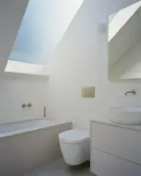 One of two bathrooms in the home, this one has a bath, while the lower-level bathroom has a shower. Brushed stainless-steel fixtures, matte white cabinetry, honed Caesarstone, and pale Claybrook tiles keep the palette simple and restrained.