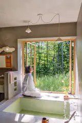 George Nakashima’s bathroom as well as Japanese onsen inspired the soaking tub downstairs. Silberkleit conceived of the space as a wet room and finished it in MicroTek by <a href="http://surecretedesign.com">SureCrete</a>. <span style="font-family: Theinhardt, -apple-system, BlinkMacSystemFont, "Segoe UI", Roboto, Oxygen-Sans, Ubuntu, Cantarell, "Helvetica Neue", sans-serif;">Ally sought an indoor/outdoor feel in the space and Marvin’s Elevate casement windows, installed to open outward like French doors, achieve the effect. <a href="http://rorypots.com/">Rory Pots</a> designed the pendants and wall sconce and <a href="https://www.furloughwoodco.com/">Silberkleit</a> made the mirror.</span>