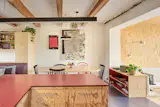 A newly installed kitchen, adding more counter and storage space, is done in pine plywood with compact-laminate countertops in the same bold red as the extension. The art is by Sarah Dubna. The <a href="https://www.dwr.com/kitchen-dining-chairs-benches/salt-chair/100193006.html">chairs</a> and table are by Ton.