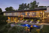 Built in 1953, this fully furnished and restored Crestwood Hills home rises above its sloping site, with walls of glass framing views of Los Angeles and the Pacific.