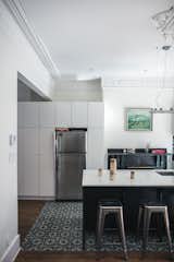 Kitchen, Refrigerator, White Cabinet, Medium Hardwood Floor, and Ceramic Tile Floor IKEA cabinets create storage around a Frigidaire refrigerator. The ornate molding maintains the historic character of the house.  Photos from Historic Montreal House Meets DIY IKEA