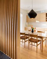 The dining area is separated from the entrance with a custom wrap-around screen that provides privacy without closing the space off completely. The slats are made of CNC’ed wood.&nbsp;