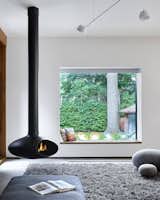 The living space that features a freestanding fireplace looks out through a seated window that perfectly frames the yard.&nbsp;