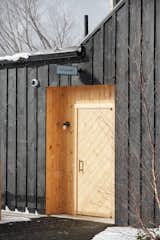 Doors, Swing Door Type, Wood, and Exterior The exterior of the structure is wrapped with board-and-batten boards that have been milled locally and finished with a dark stain. It’s balanced out by sections and accents made with natural pine and cedar.  Photo 1 of 172 in Houses by Adam neilson from A Modern Mountain Lodge That Will Make You Love Winter Like Never Before