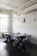 To create a place where employees and visitors can have lunch family style, they brought in a large dining table by James Perse. The hanging light is the Lampada 046 by Dimore Studio.
