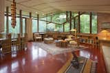 The open living space is surrounded by large, angular pieces of glass and sits on a Colorundum floor painted in Cherokee Red—a material and color that Wright often used in his work. This space also includes a brick wood-burning fireplace.